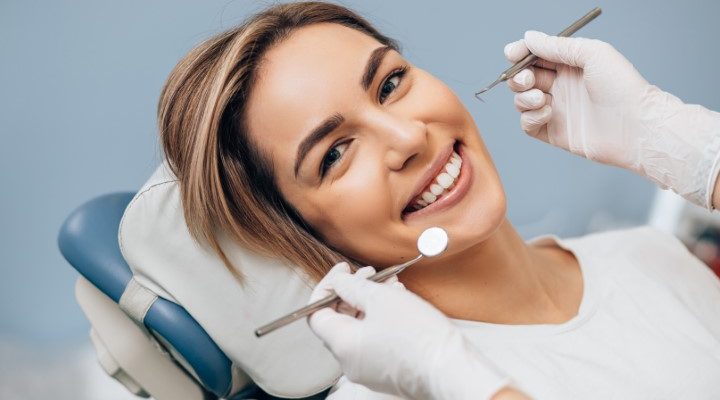 portrait of young caucasian woman with perfect smile in dental office, come to treat spoiled teeth, look at camera